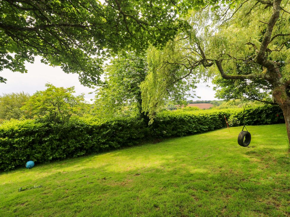A garden with a tire swing and trees at The Cow Shed in 