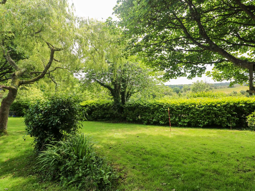 A garden with trees and grass at The Cow Shed in 