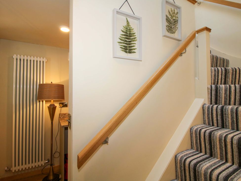 A stairway with a lamp and wall art at The Hideaway in Longden