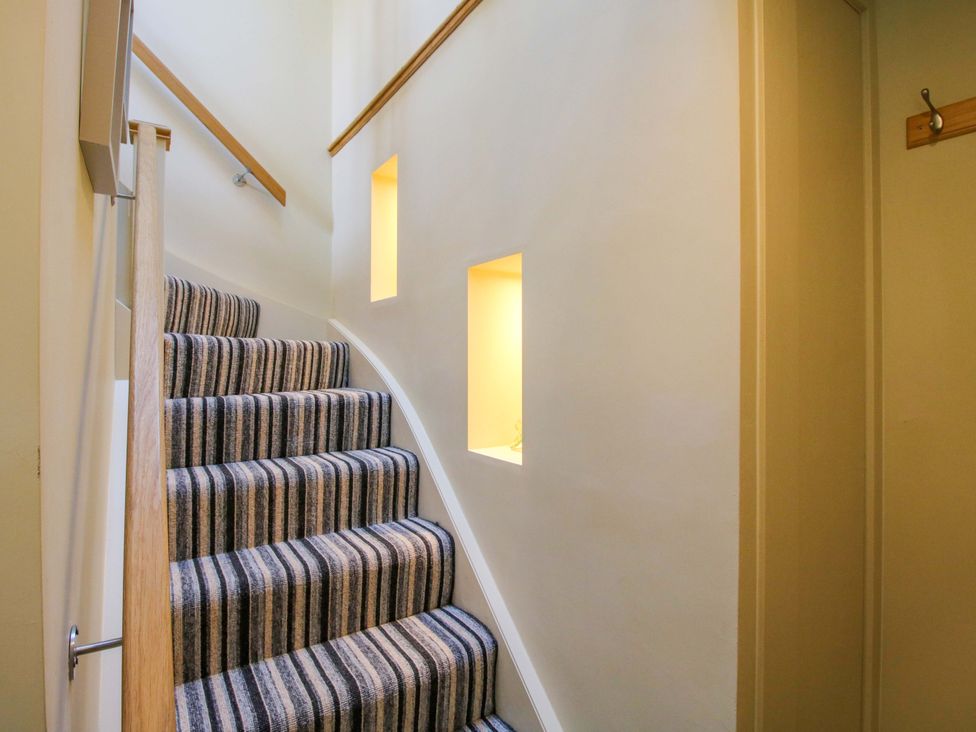A staircase with striped carpet and illuminated wall niches at The Hideaway in Longden