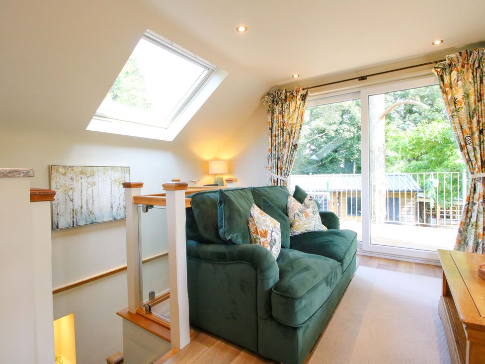 A living room with a green sofa and large window at The Hideaway in Longden
