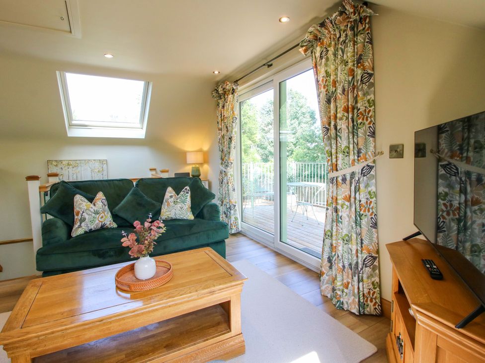 A living room with a green couch and wooden coffee table at The Hideaway in Longden