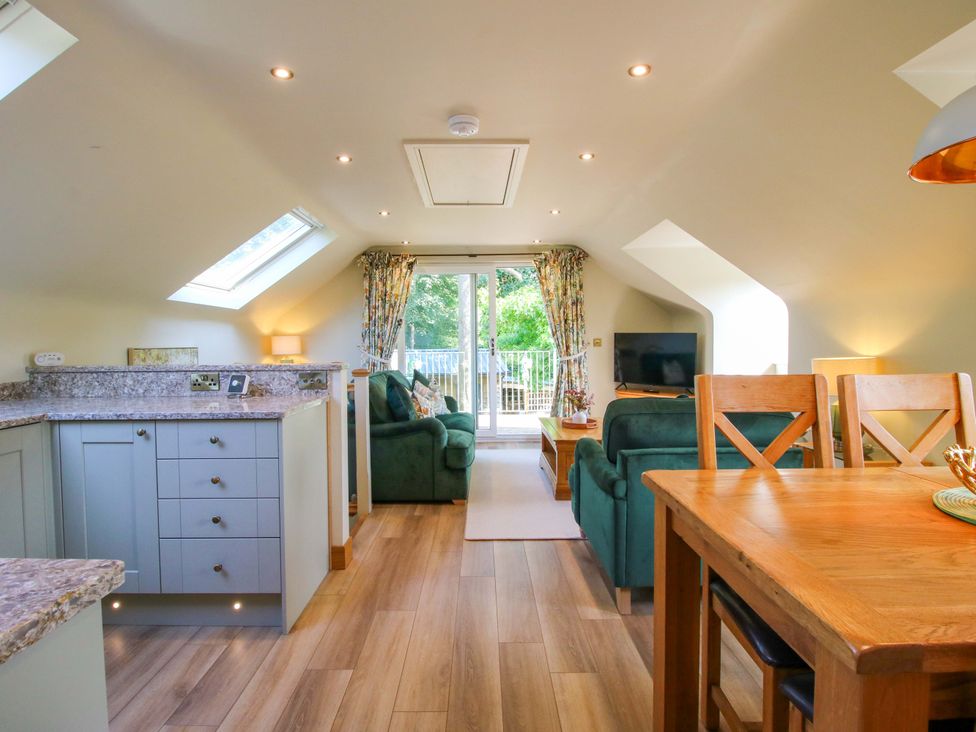 A living room with a kitchen area and dining table at The Hideaway in Longden