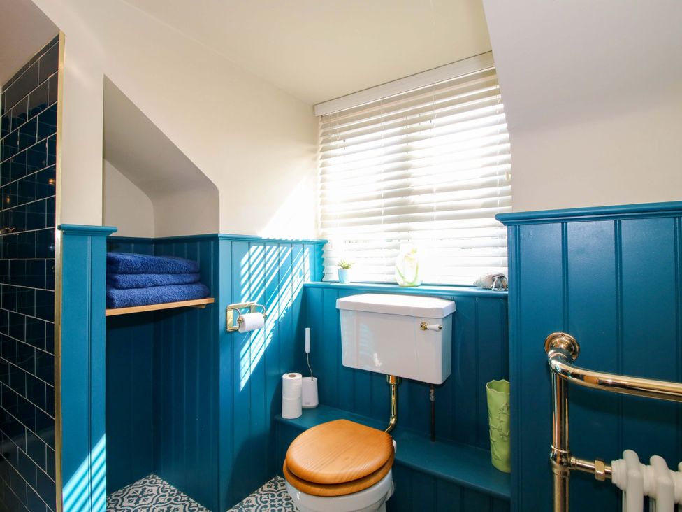A bathroom with a toilet and towels on a shelf at The Hideaway in Longden