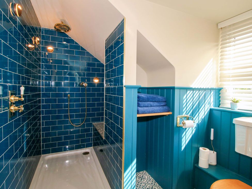 A bathroom with a shower and blue towels at The Hideaway in Longden