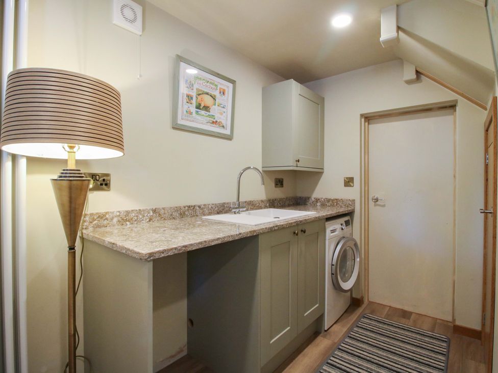 A utility room with a sink and washing machine at The Hideaway in Longden