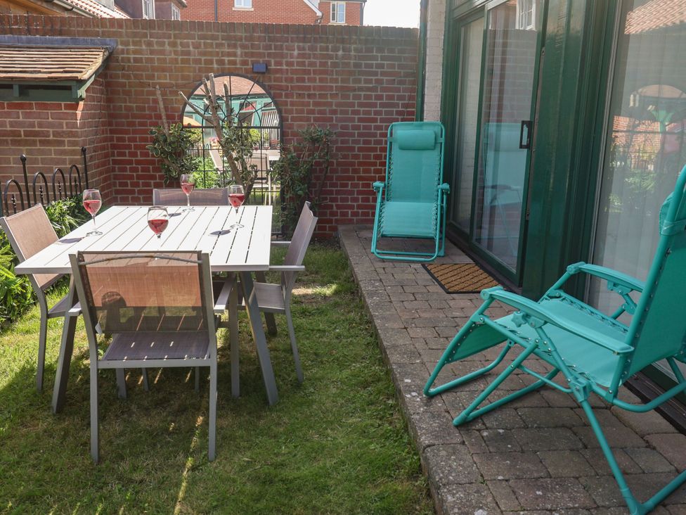 A garden with a table, chairs, and wine glasses at 6 The Mews Felixstowe, Suffolk