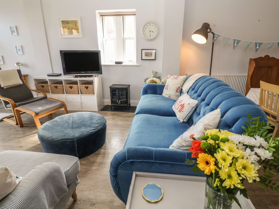 A living room with a blue sofa and a television at 6 The Mews, Felixstowe, Suffolk