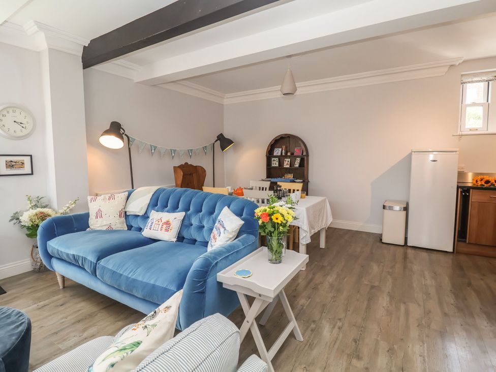 A living room with a blue sofa and a dining table at 6 The Mews in Felixstowe, Suffolk