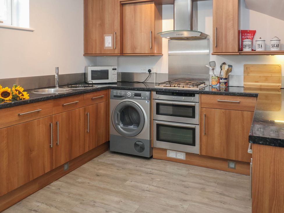 A kitchen with appliances and wooden cabinets at 6 The Mews Felixstowe, Suffolk