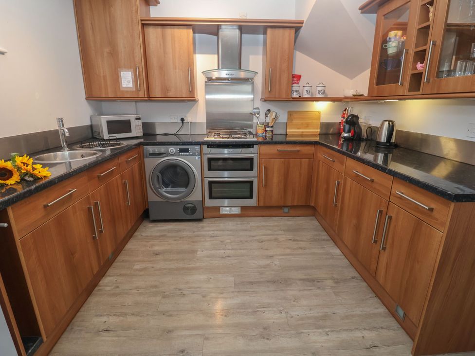 A kitchen with wooden cabinets and appliances at 6 The Mews, Felixstowe, Suffolk