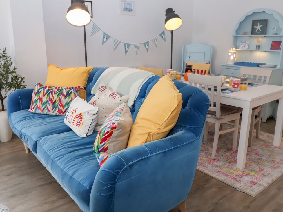 A living room with a blue sofa and dining area at Old Felixstowe, Bath Road, Felixstowe, Suffolk
