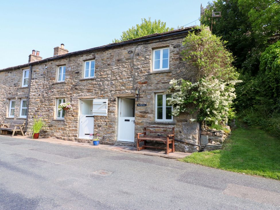 A stone cottage with a front door and bench at The Old Dairy in Richmond