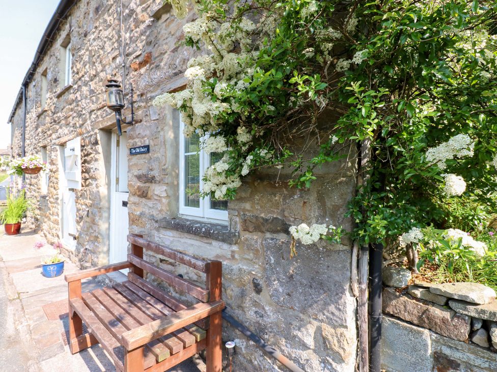 An outdoor area with a stone wall, a bench, and flowers at The Old Dairy in Richmond