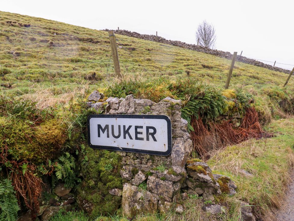 A sign for Muker on a stone wall in a grassy area at The Old Dairy Richmond