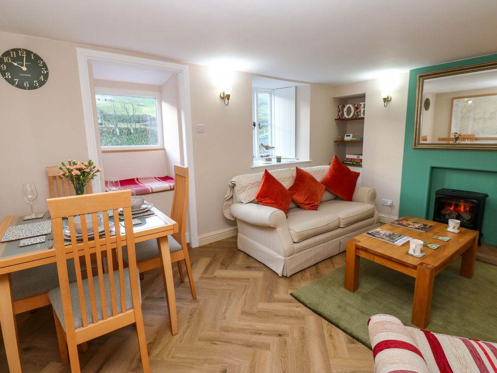 A living room with a table and chairs, sofa and fireplace at The Old Dairy in Muker