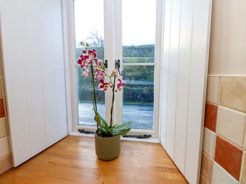 A window with an orchid plant on a ledge at The Old Dairy in Muker