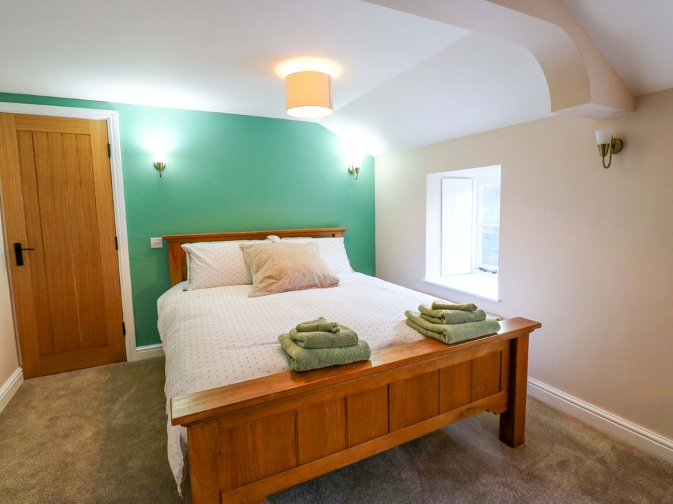 A bedroom with a bed and towels at The Old Dairy in Muker