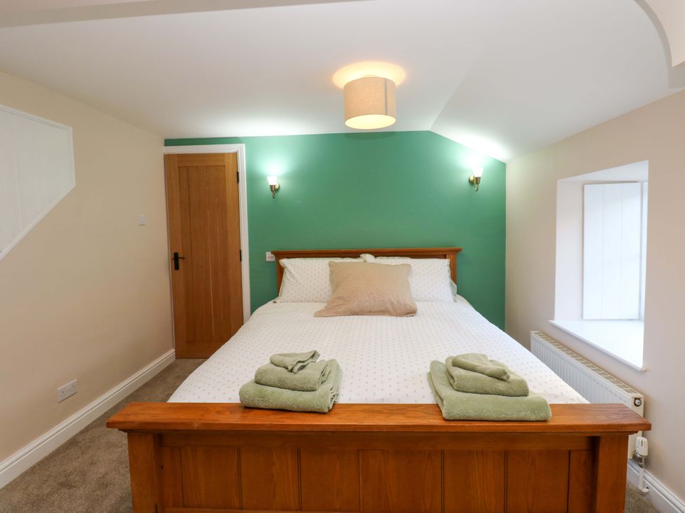 A bedroom with a bed and towels at The Old Dairy in Muker