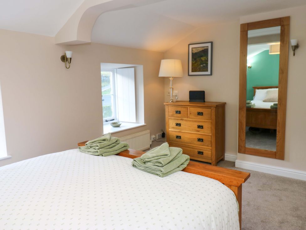 A bedroom with a bed and wooden furniture at The Old Dairy Muker