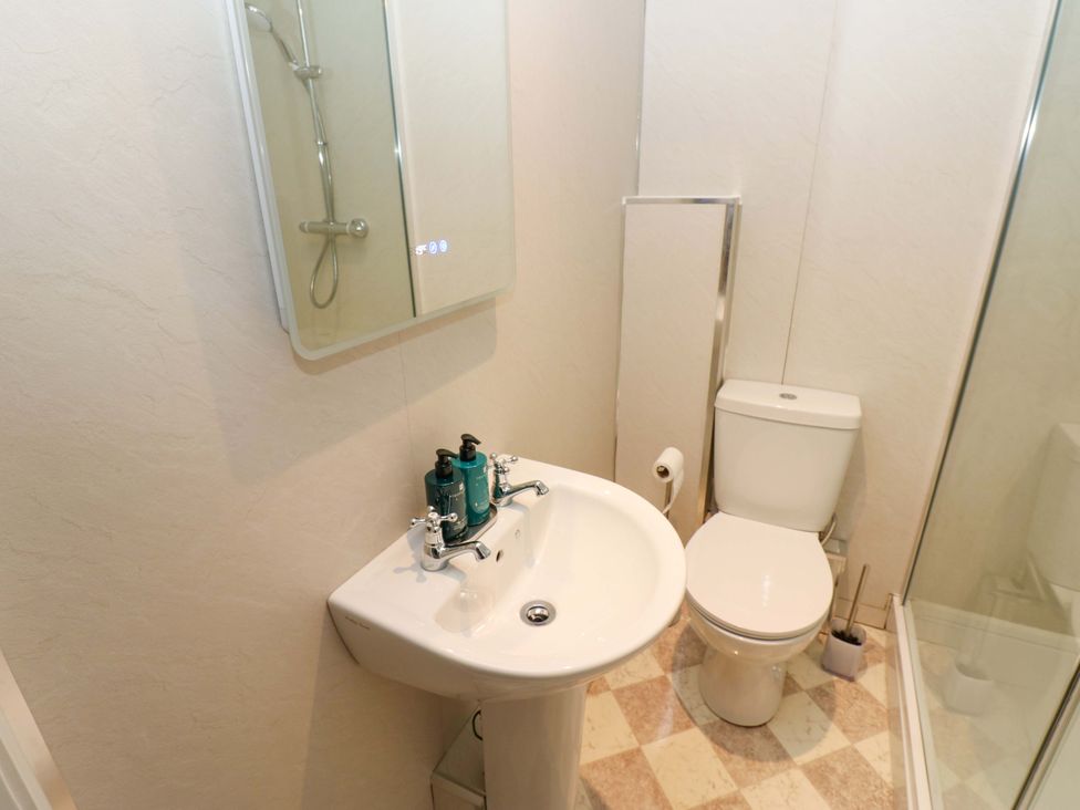 A bathroom with a sink, toilet, shower and mirror at The Old Dairy in Muker