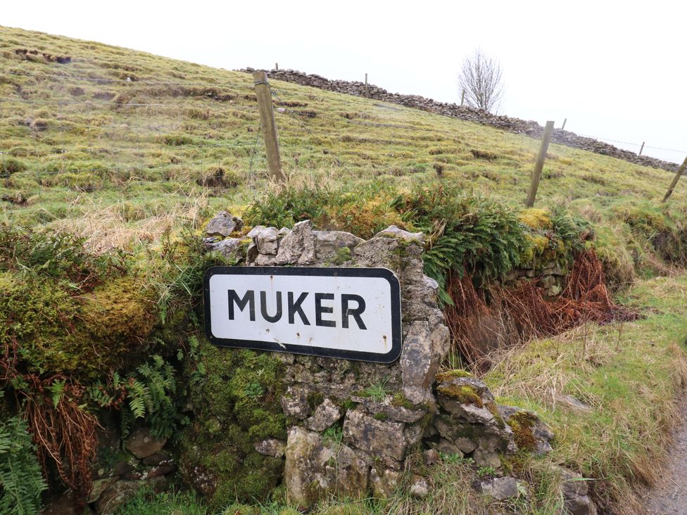 A sign indicating Muker on a grassy landscape at The Old Dairy Muker