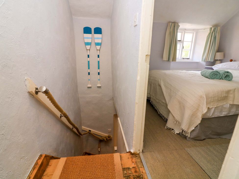 A staircase leading to a bedroom with towels and a lamp at 2 The Square Hope Cove