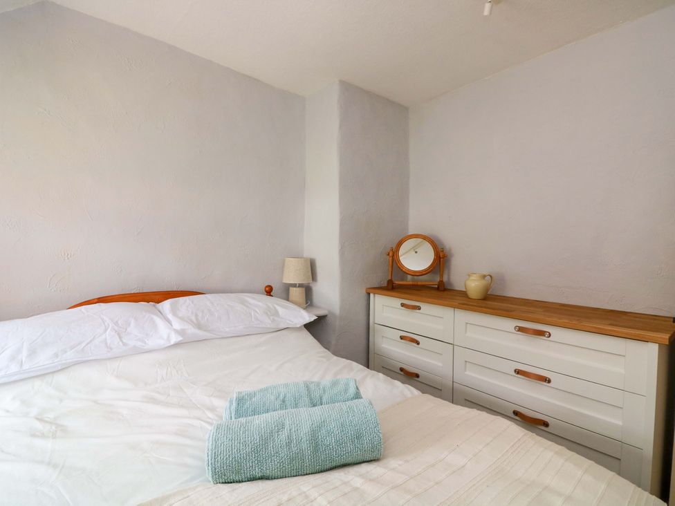 A bedroom with a bed, dresser and mirror at 2 The Square Hope Cove