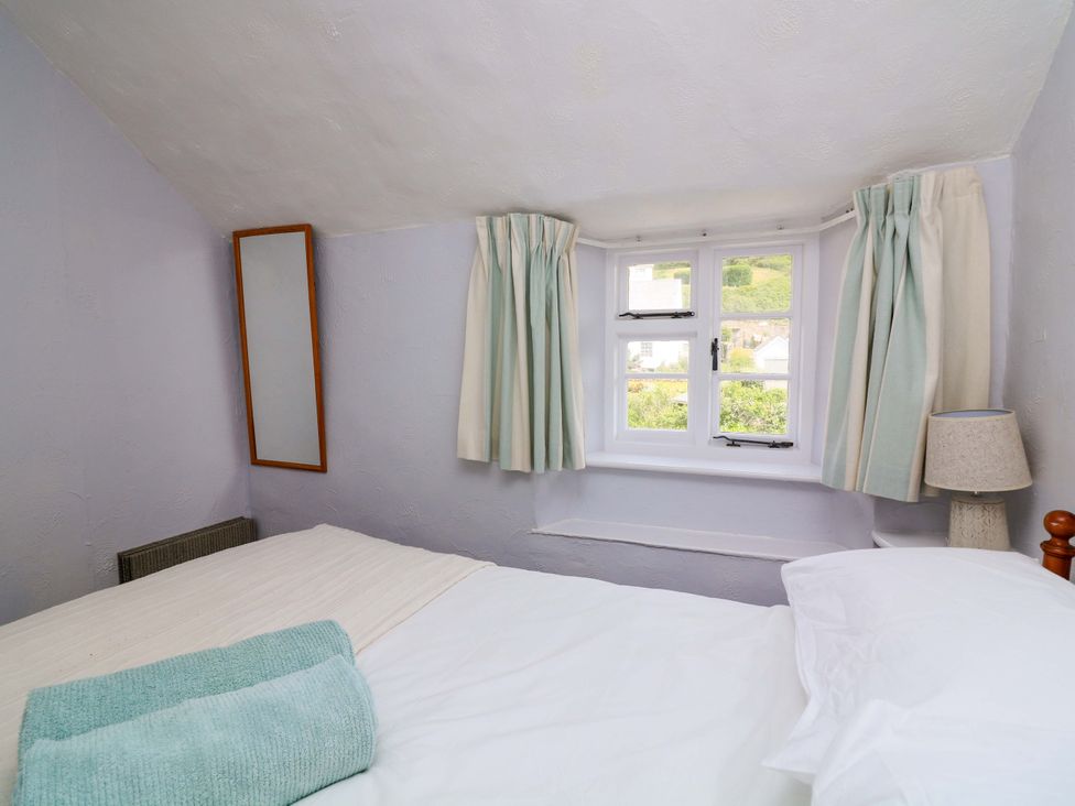 A bedroom with a bed and window at 2 The Square Hope Cove