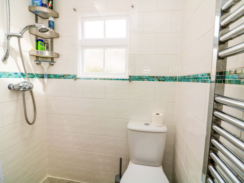 A bathroom with a shower, toilet, and window at 2 The Square Hope Cove