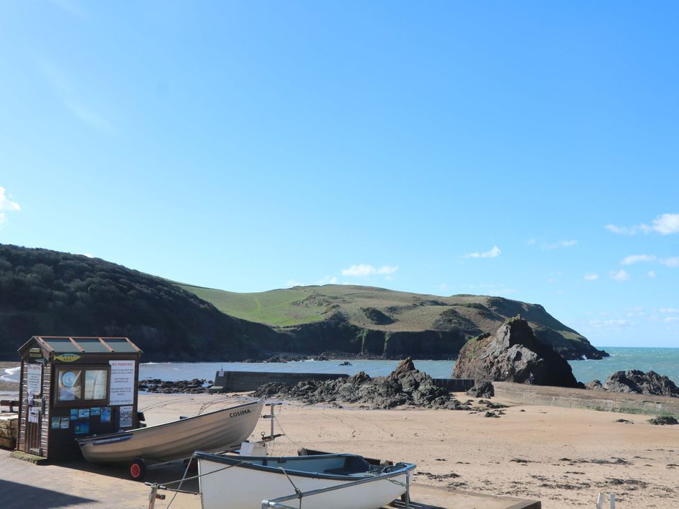 A beach with boats and an information board at 2 The Square Hope Cove