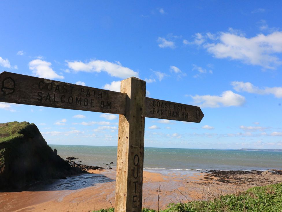 A signpost indicating coast paths to Salcombe and Bantam near the beach