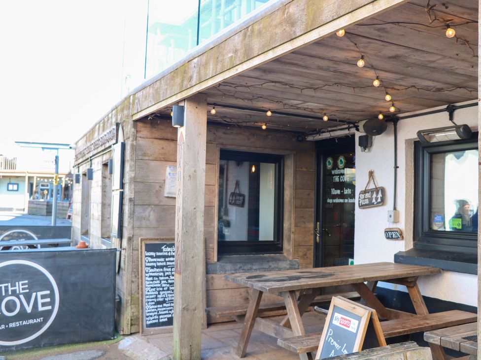 An outdoor seating area with tables and a menu board at The Cove in Hope Cove