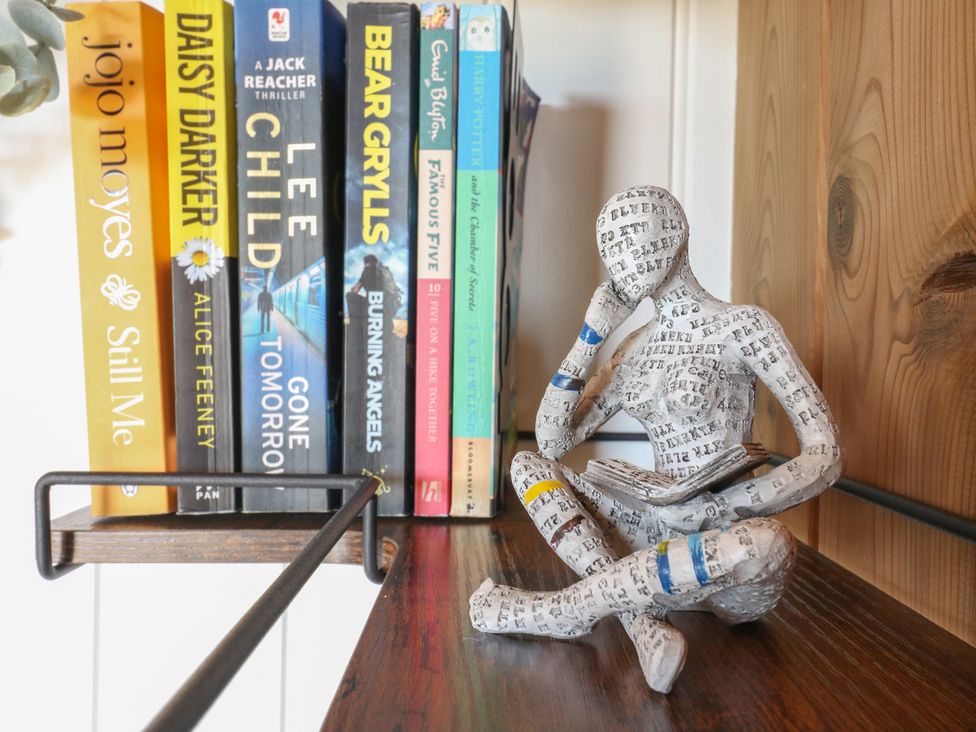 A wooden shelf with several books and a small figurine of a person reading at The Heron in Lode near Bottisham