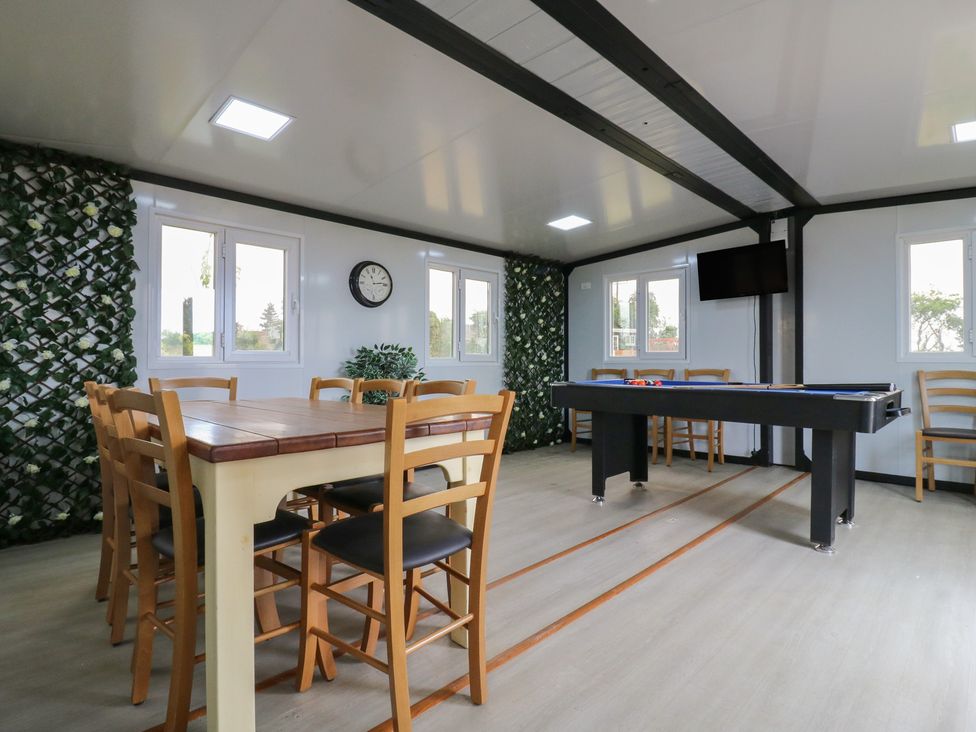 A recreational room with a dining table and chairs a pool table and a wall clock at The Heron in Lode near Bottisham