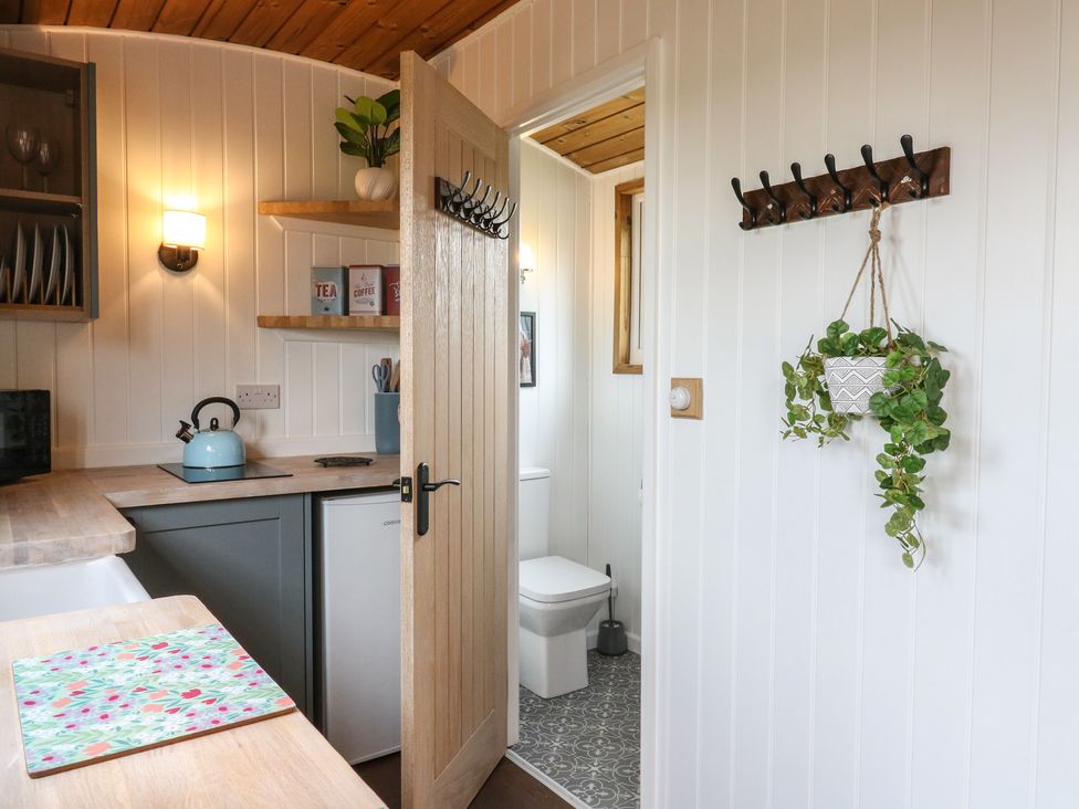 A kitchen with wooden counters and a small fridge next to a door leading to a bathroom at Barn Owl in Lode near Bottisham
