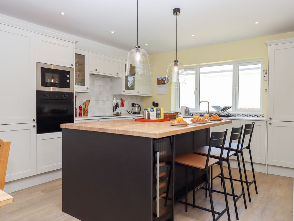 A kitchen with an island and stools at Clova in Brixham