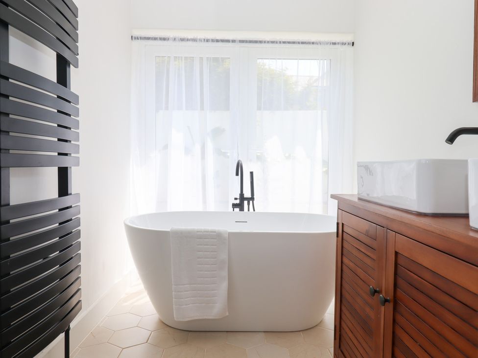 A bathroom with a bathtub and a cabinet at Clova in Brixham