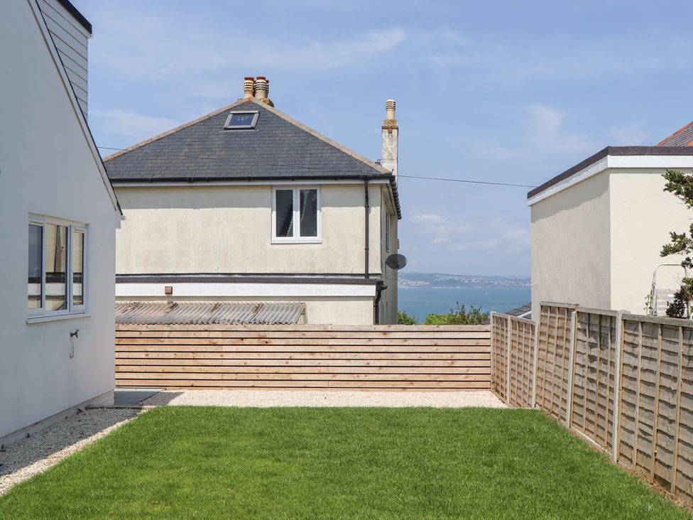 A garden with grass and wooden fence at Clova in Brixham