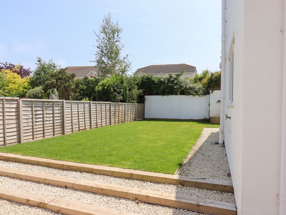 A garden with grass and a wooden pathway at Clova in Brixham