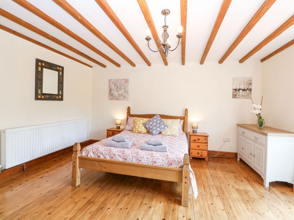 A bedroom with a bed and side tables at Lakeside Barn Aylsham