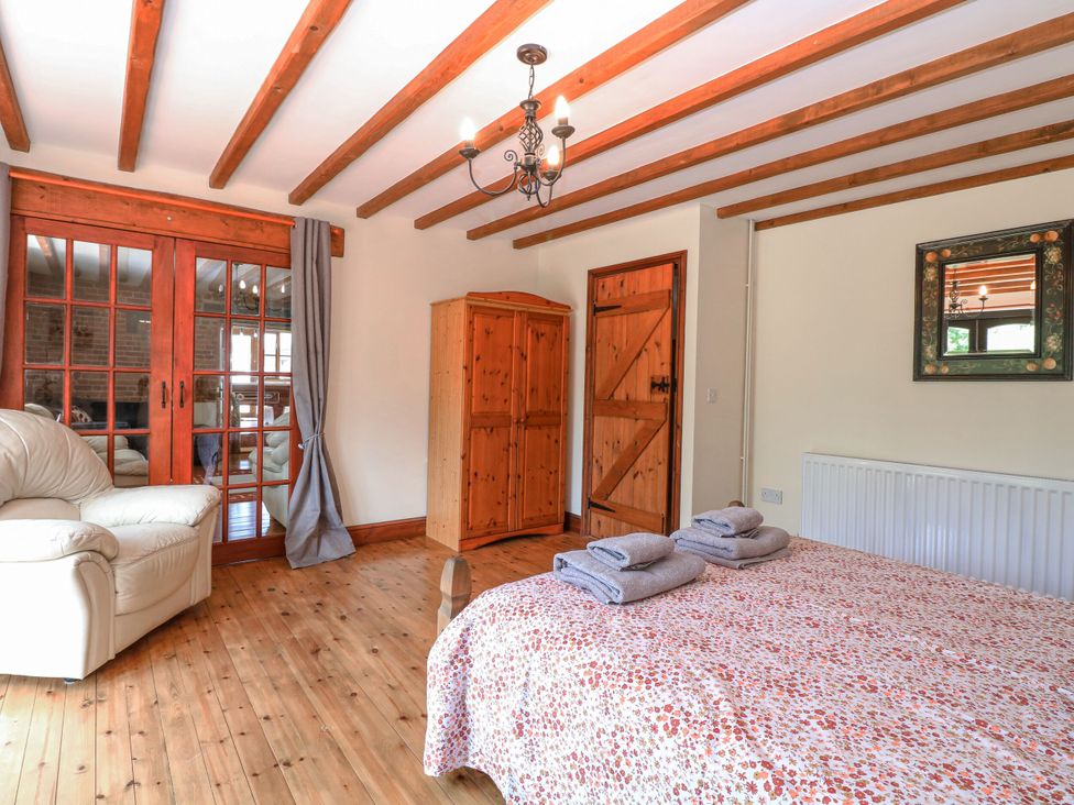 A bedroom with a bed and wardrobe at Lakeside Barn Aylsham