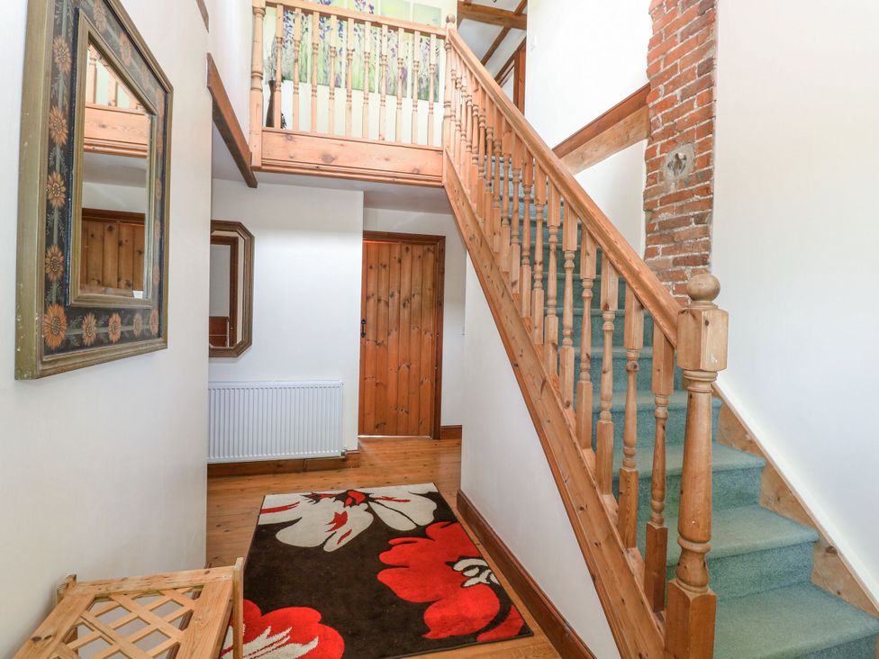 A hallway with stairs and a mirror at Lakeside Barn Aylsham