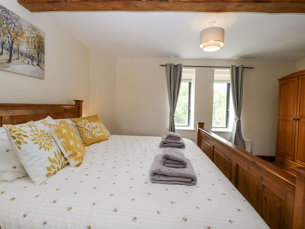 A bedroom with a bed and wardrobe at Lakeside Barn in Aylsham