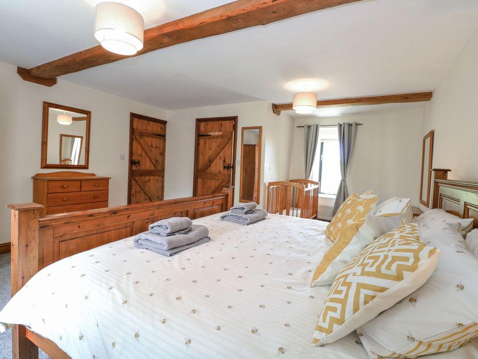 A bedroom with a bed and dresser at Lakeside Barn Aylsham