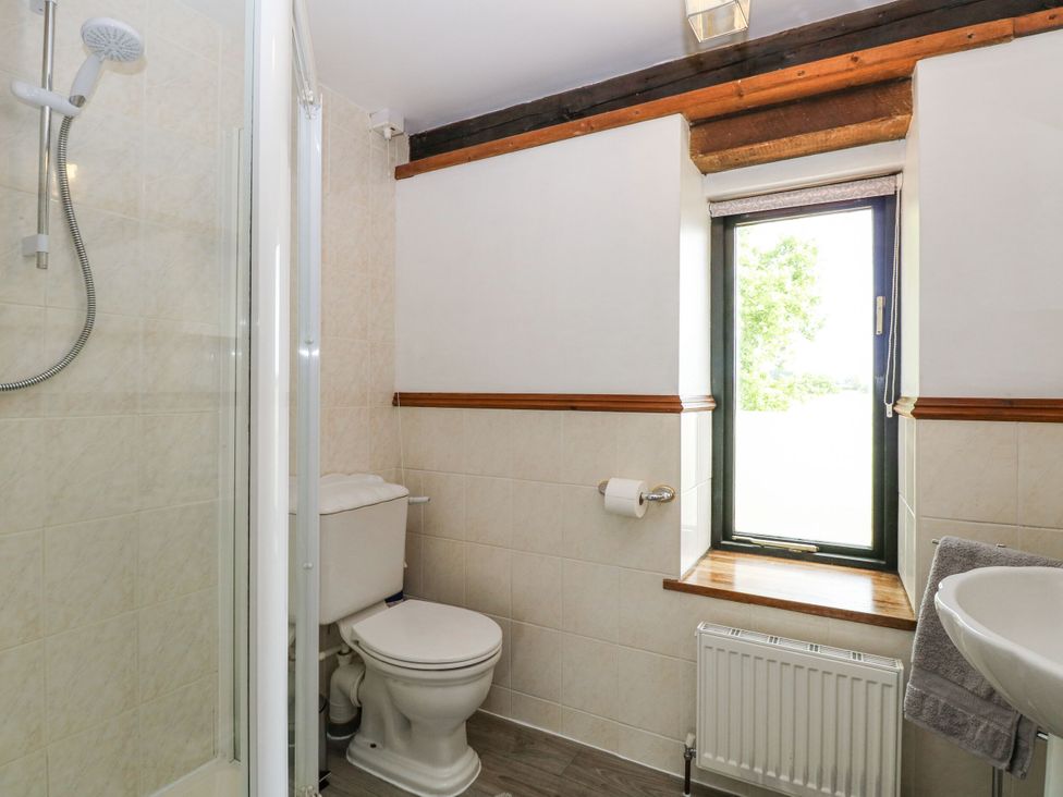 A bathroom with a shower, toilet, and sink at Lakeside Barn Aylsham