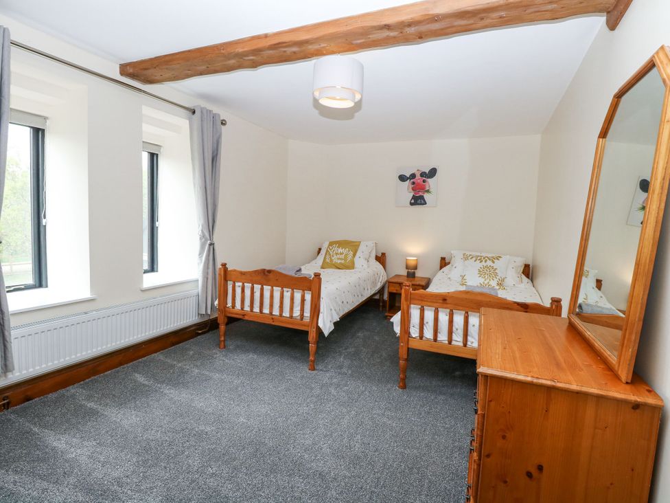 A bedroom with two single beds and a mirror at Lakeside Barn Aylsham
