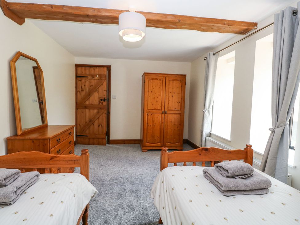 A bedroom with twin beds and wooden furniture at Lakeside Barn Aylsham