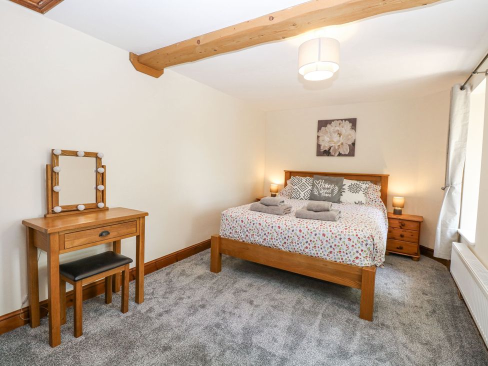 A bedroom with a bed, nightstands and a vanity at Lakeside Barn Aylsham