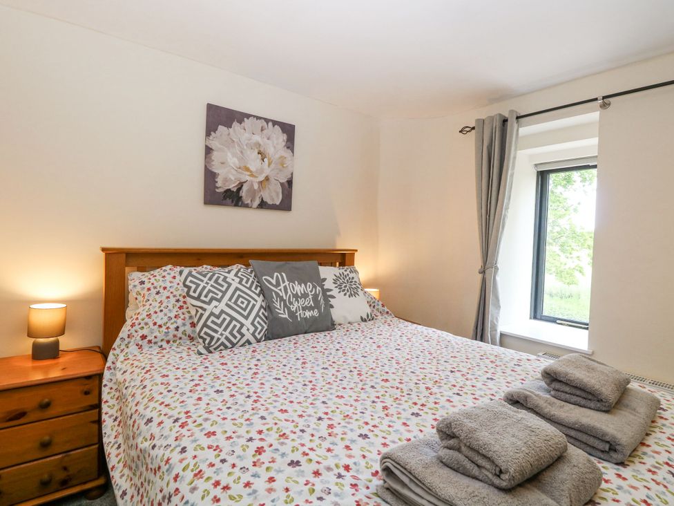 A bedroom with a bed and a window at Lakeside Barn Aylsham